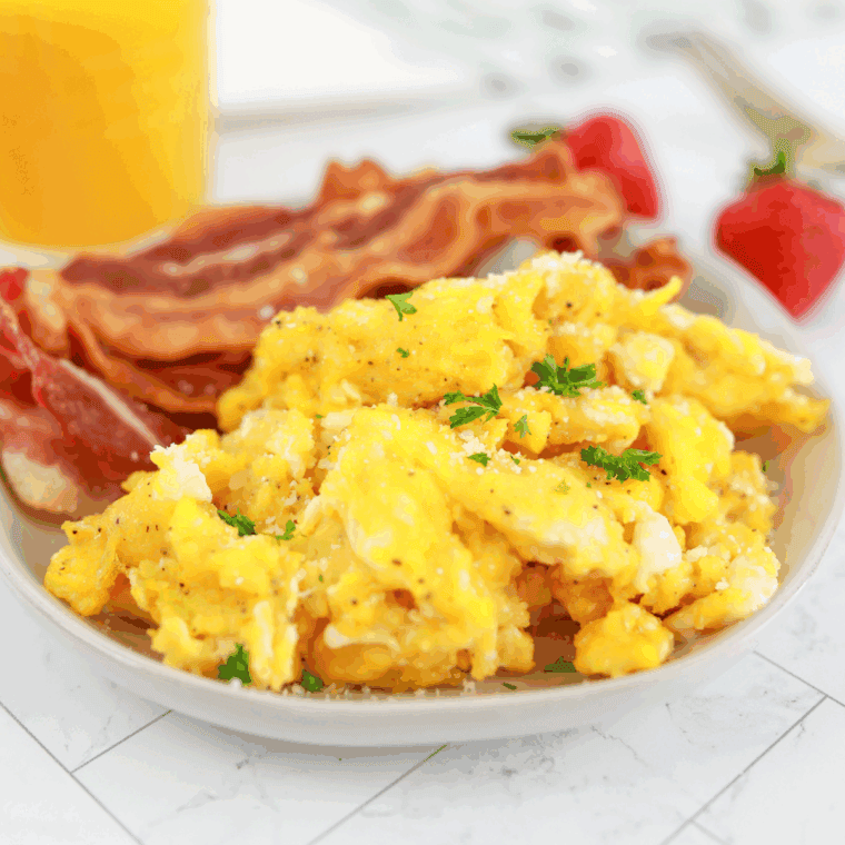 Plate of Waffle House Scrambled Eggs  on kitchen table. with bacon and orange juice.