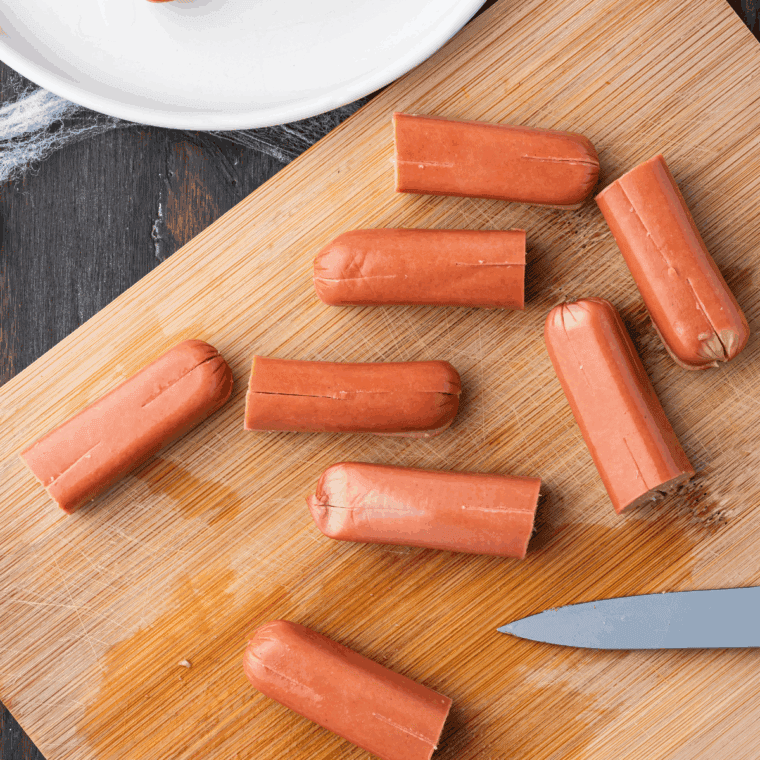 Hot dog sliced in half, with one half cut vertically into smaller sections for spider legs.