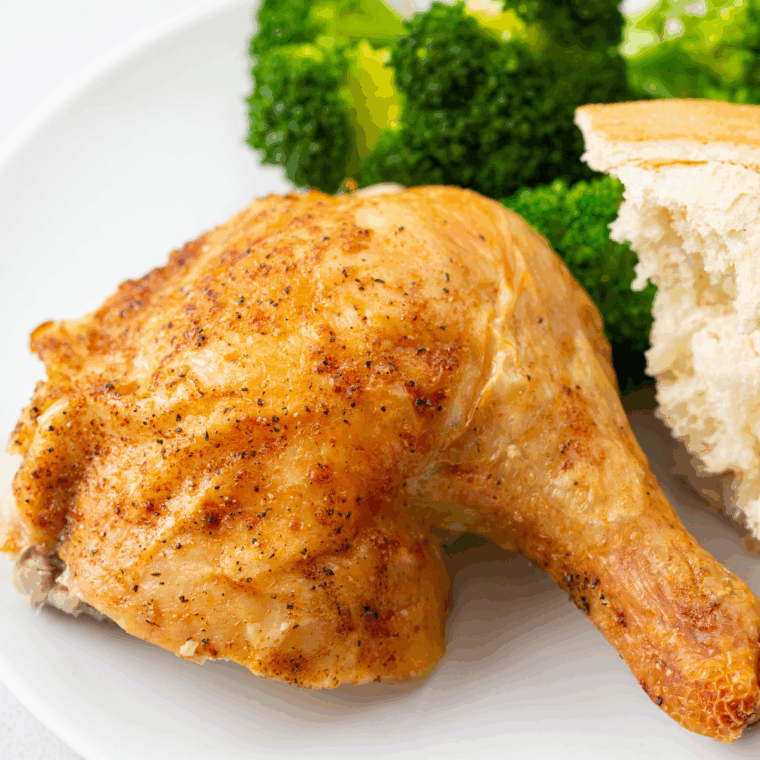 Golden roasted Barefoot Contessa Cornish Hen served on a platter with herbs.