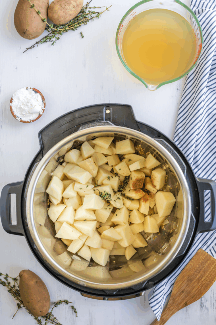 Flour sprinkled over sautéed vegetables, stirred with chicken broth, diced potatoes, and fresh thyme in the Instant Pot.
