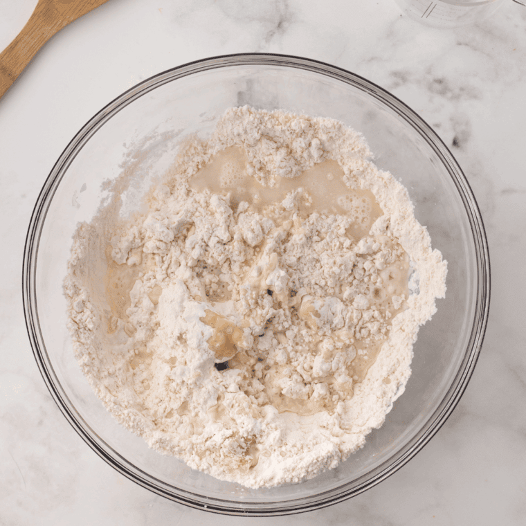 Mixing flour, baking powder, salt, oil, and warm water in a large bowl to form soft dough.