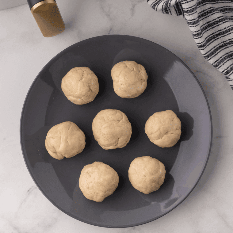 Dividing dough into balls and rolling each into thin, round tortillas with a rolling pin.