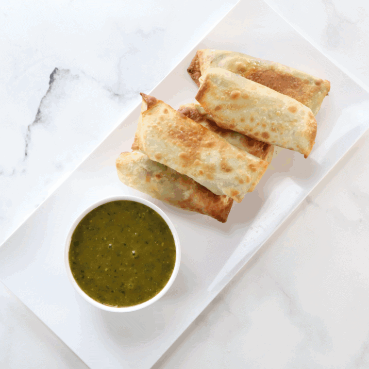Crispy homemade BJ’s Avocado Egg Rolls on a plate with cilantro-lime dipping sauce.