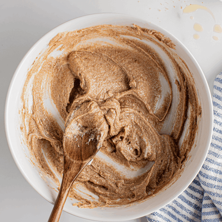 Medium bowl with softened cream cheese, brown sugar, cinnamon, vanilla, and a pinch of salt being mixed.
