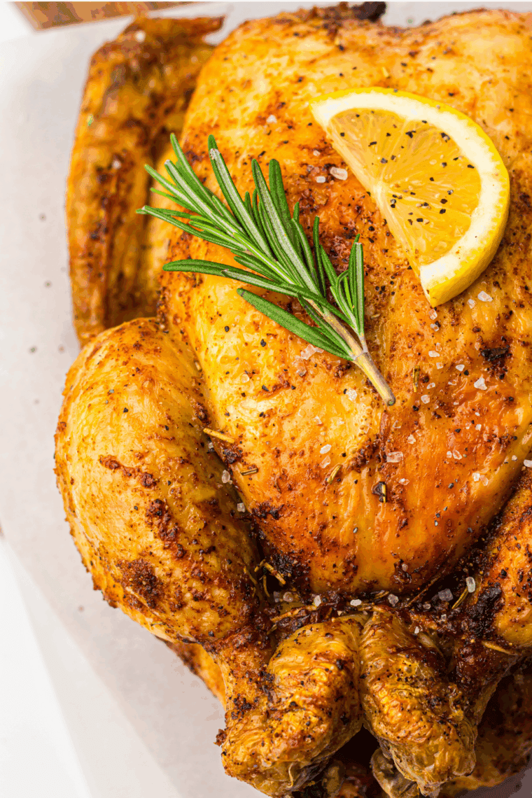 Golden roasted Ina Garten chicken with crispy skin, fresh herbs, and lemon on a serving platter.