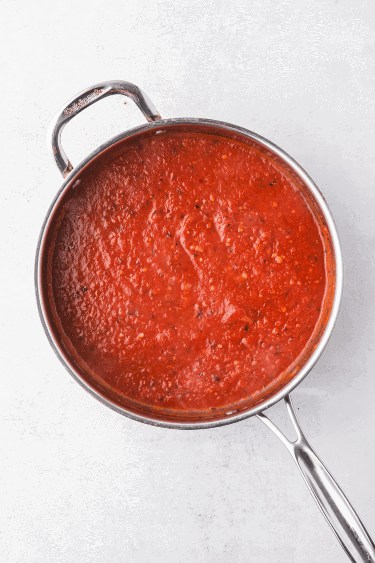 Adding red wine to the skillet, then stirring in crushed tomatoes, parsley, salt, and pepper to create a flavorful marinara base.