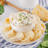 A creamy bowl of Lipton Onion Soup Spinach Dip served with crackers and fresh veggies on a wooden board, ready for a party snack.