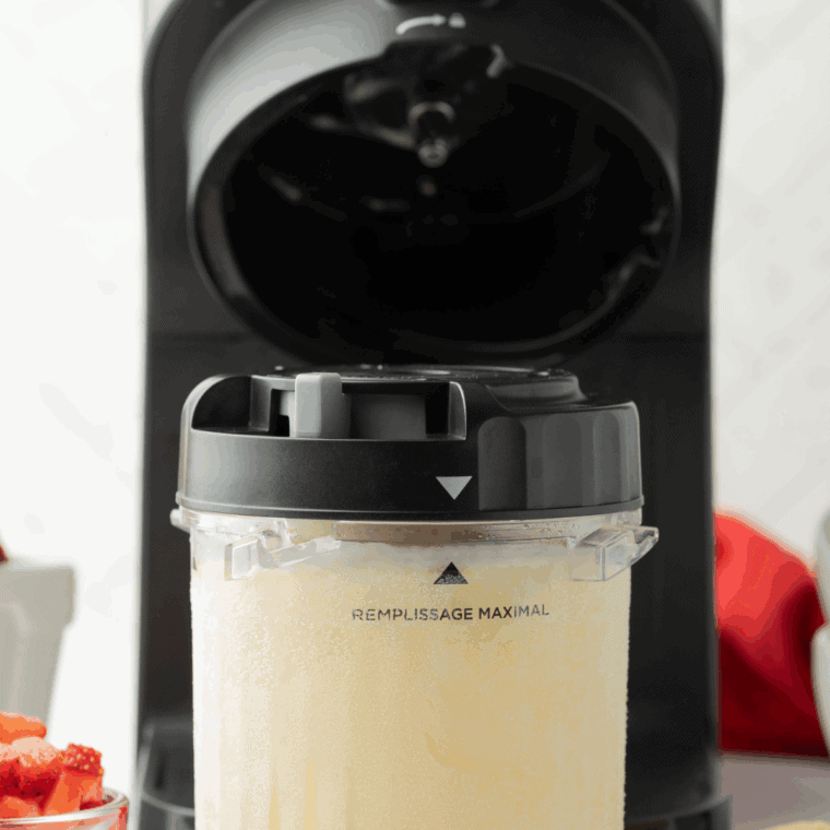 Inserting the frozen pint into the Ninja Creami machine and churning until smooth and creamy Butterbeer ice cream is formed.