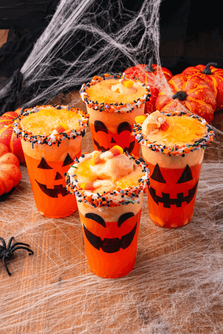 Fanta Jack O’Lantern Halloween Floats made with orange soda, sherbet, and Halloween sprinkles served in cups decorated with jack-o-lantern faces.