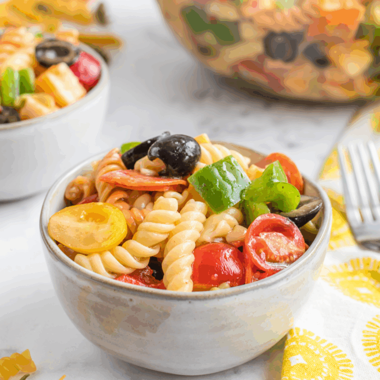 Stirring the chilled pasta salad, garnished with extra cheese or fresh herbs, ready to serve.