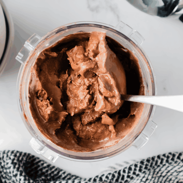 Finished chocolate malt ice cream scooped into bowls or cones, topped with chocolate syrup, crushed malted milk balls, and whipped cream.