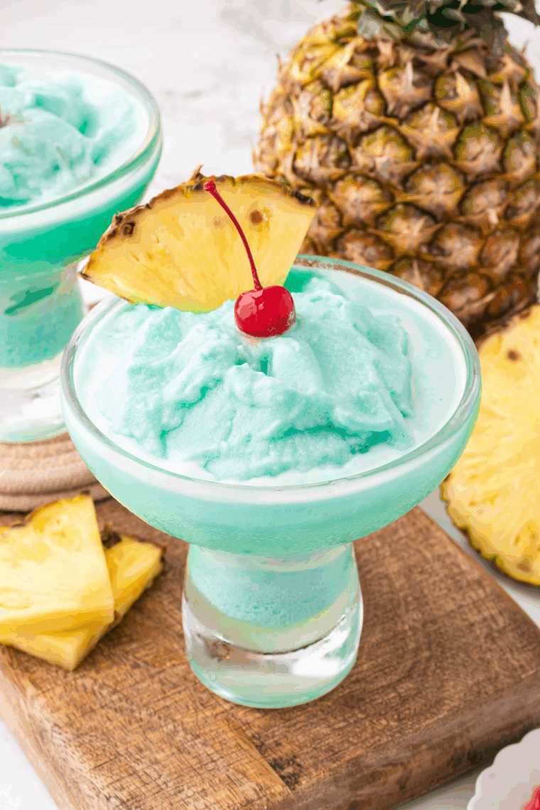 Frozen Blue Hawaiian cocktail made in a Ninja Slushi machine, served in a tall glass with pineapple wedge and cherry garnish.