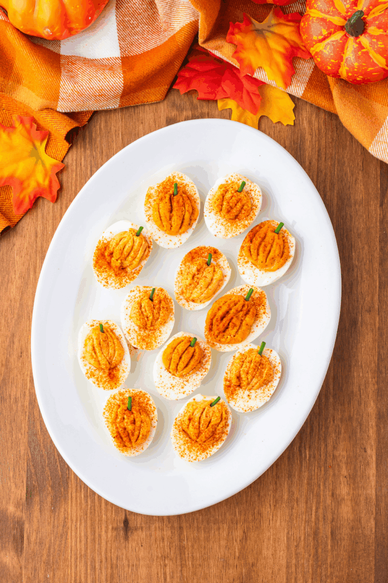 Close-up of a pumpkin-shaped deviled egg with scored ridges and a chive stem
