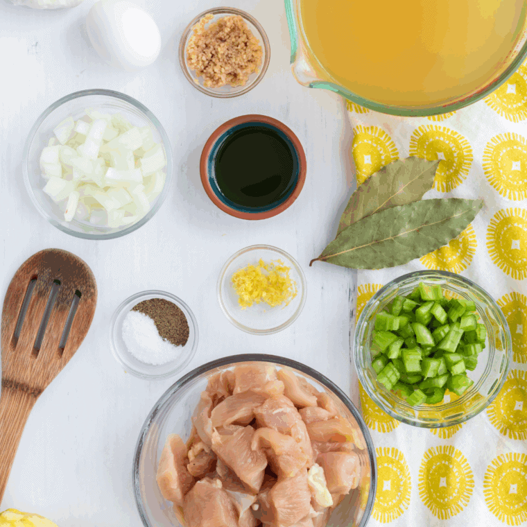 Chicken pieces marinating in a clear, oil-based Mediterranean Marinade, speckled with dried oregano and chopped garlic cloves.
