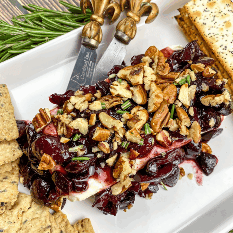 Cream Cheese Spread topped with warm cherry sauce on a white serving plate.