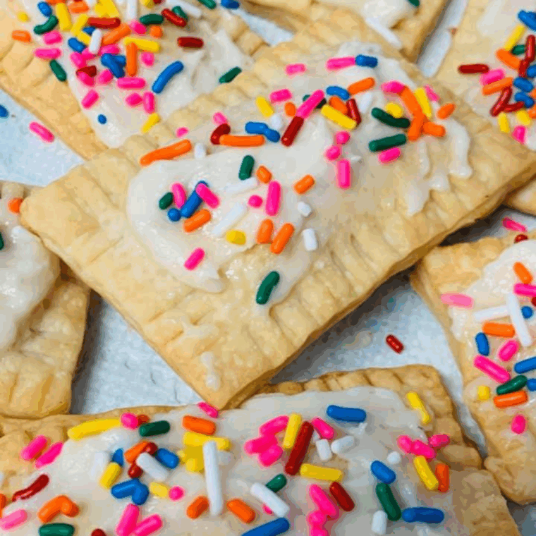 Golden air fryer raspberry pop-tarts drizzled with glaze and colorful sprinkles on a plate.