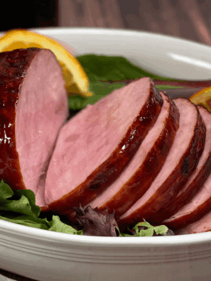 Sliced, fully cooked Amish ham with a sweet, sticky glaze ready for carving.