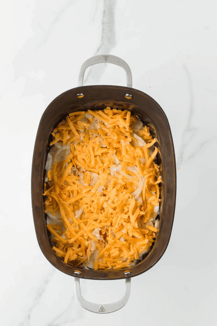 Sprinkling cheddar and Parmesan cheese over potato layers