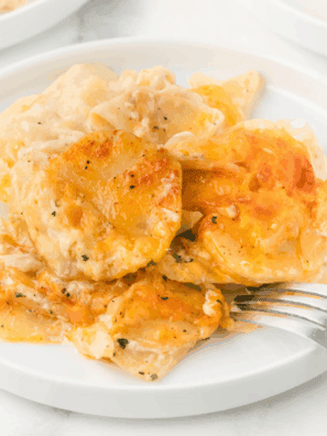 Golden brown and bubbly baked dish of Ruth's Chris style Potatoes au Gratin, showing layers of sliced potatoes covered in creamy cheese sauce.