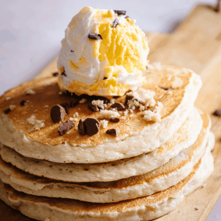 Golden, fluffy Denny’s-style pancakes stacked on a plate with butter and syrup.