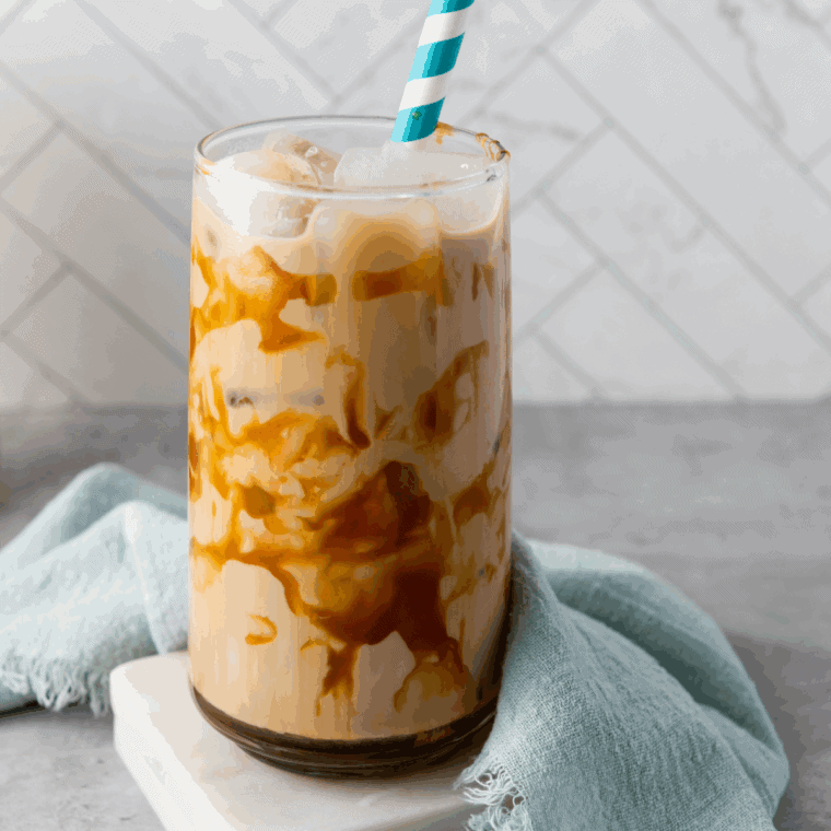 Glass of iced coffee with ice cubes and a splash of milk, styled like First Watch.