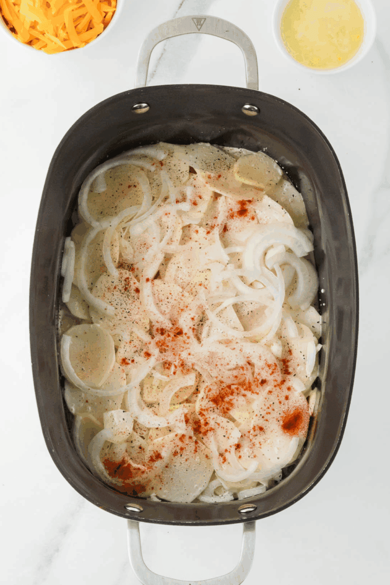 Multiple layers of potatoes, cheese, and seasonings stacked: