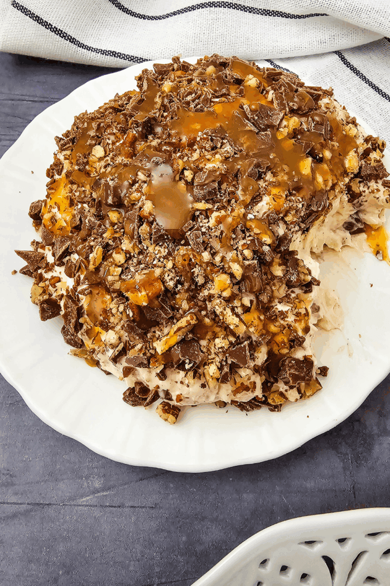 Easy Snickers Cheese Ball rolled in chopped peanuts, served on a platter with vanilla wafers and pretzels.