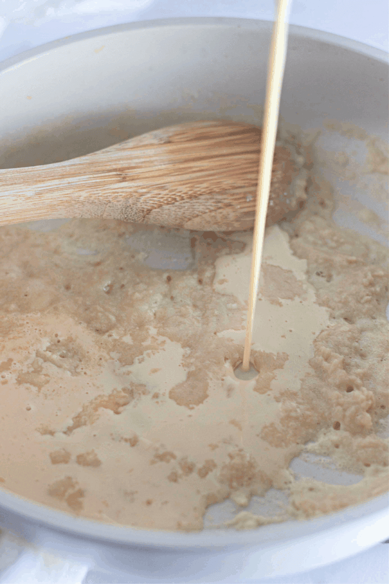 Whisking butter and flour in a saucepan, then adding turkey drippings and broth to make smooth gravy.