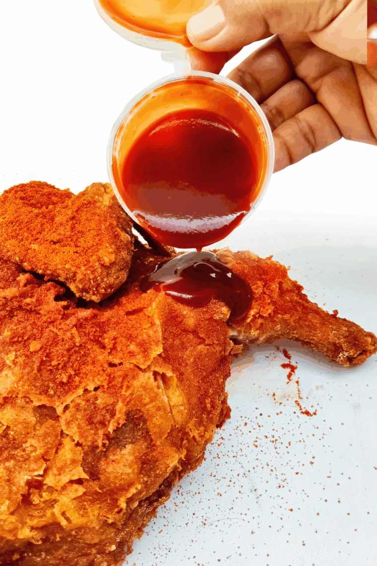 Brushing Valentina Hot Sauce on fried chicken.