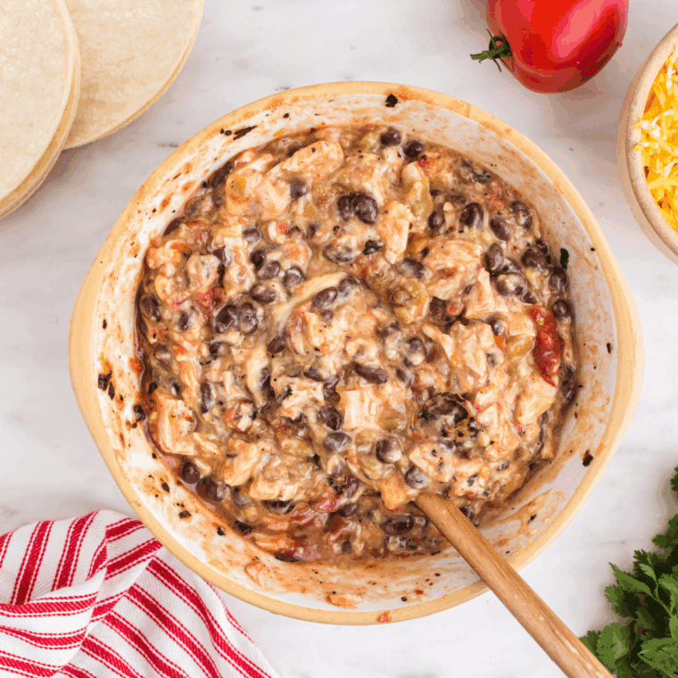 Creamy sauce mixture in bowl with spices and tomatoes.