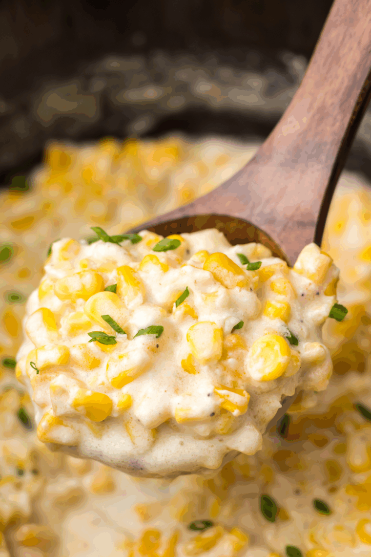 Slow cooker creamed corn cooking on low heat, stirred until smooth, creamy, and ready to serve warm.