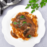 Homemade Texas Roadhouse brown gravy served in a small bowl with a spoon.