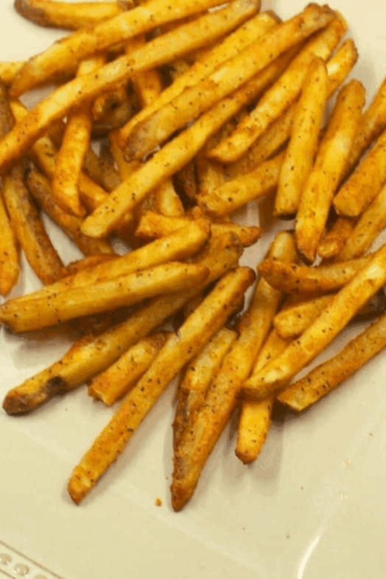 crispy air fryer fries coated with tangy dill pickle Grinch salt seasoning in a shaker bag