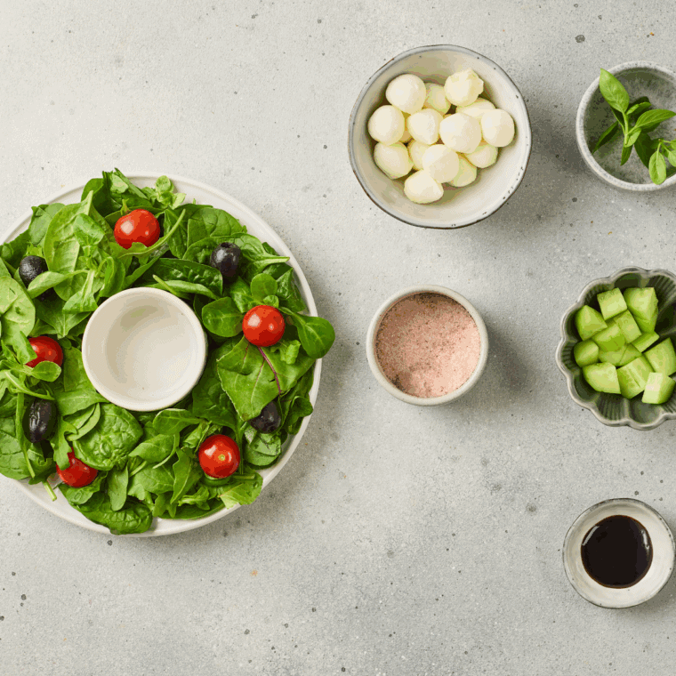 Mixed greens arranged in a circular shape on a platter forming a wreath base.