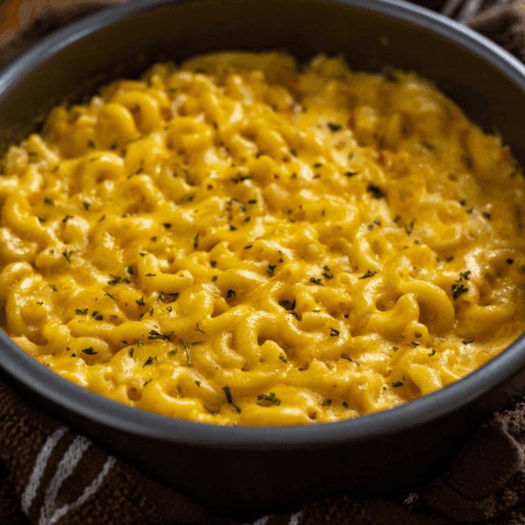 Combining cooked macaroni with cheese sauce, coating noodles evenly.