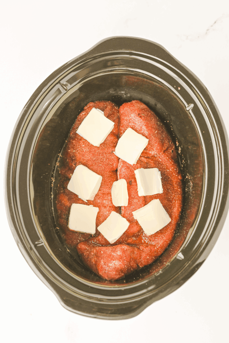 Sliced slow cooker pork tenderloin resting, then returned to broth before serving.