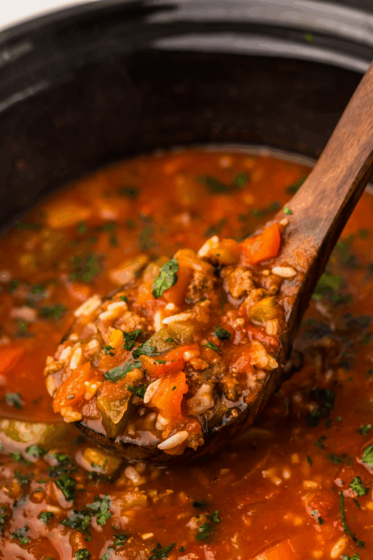 A white bowl filled with hearty Slow Cooker Stuffed Pepper Soup topped with fresh parsley and shredded cheese.