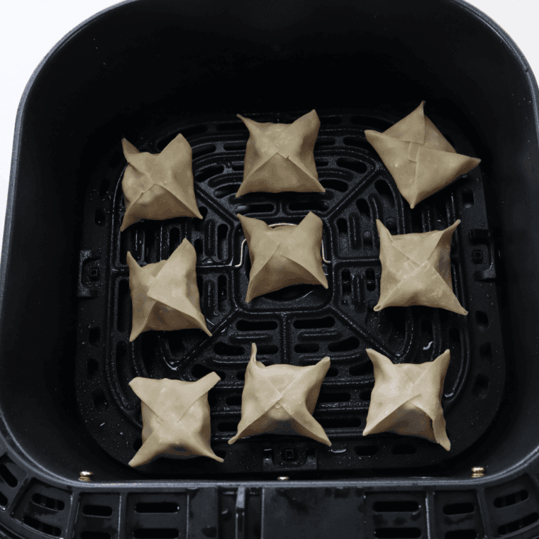 Wontons on air fryer tray, sprayed with olive oil for crispiness