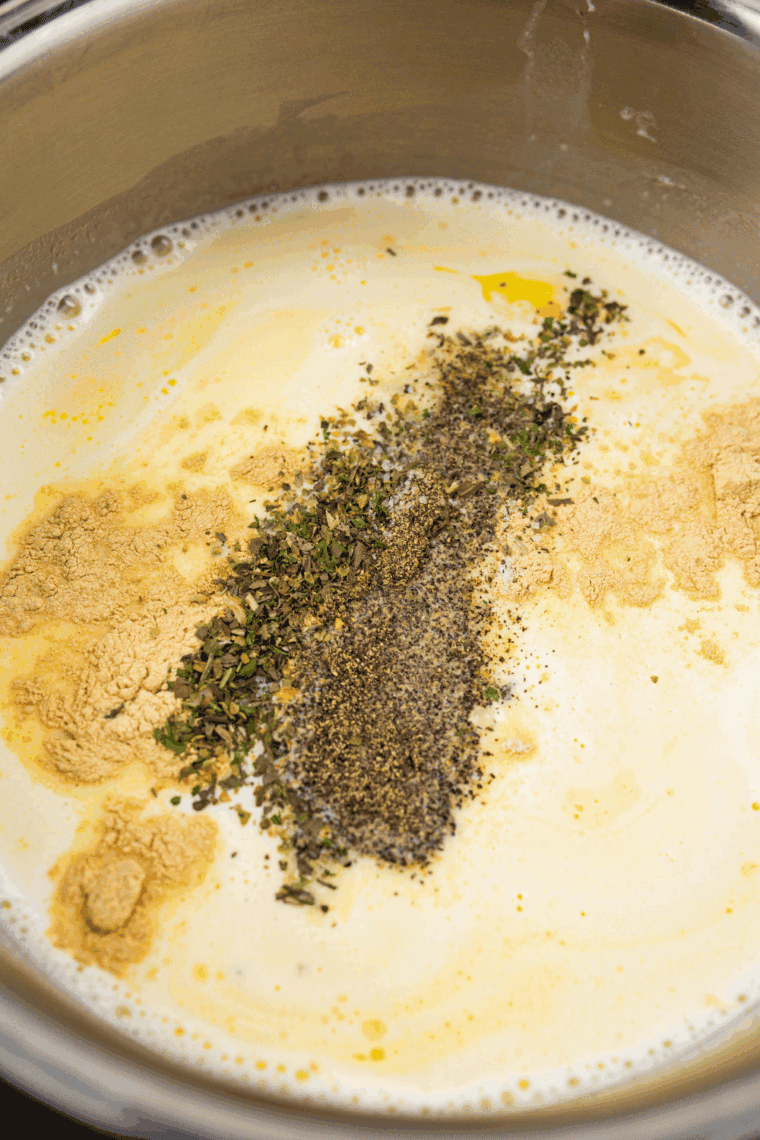 Heavy cream being poured into butter and garlic, whisked together