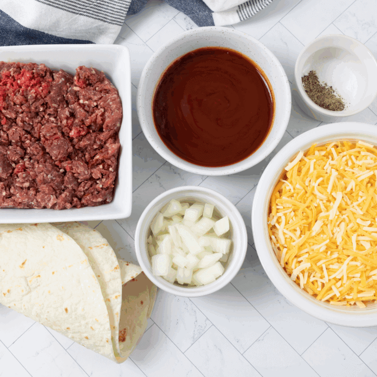Ingredients for Blackstone griddle taco meat: ground beef, onion, garlic, and taco spices