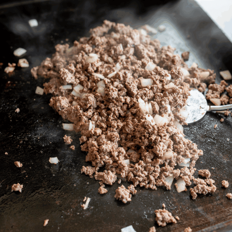 Ground beef browning and breaking apart on the Blackstone griddle for taco meat
