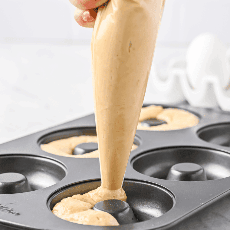 Rolling out dough and cutting donut shapes with donut cutter on floured surface
