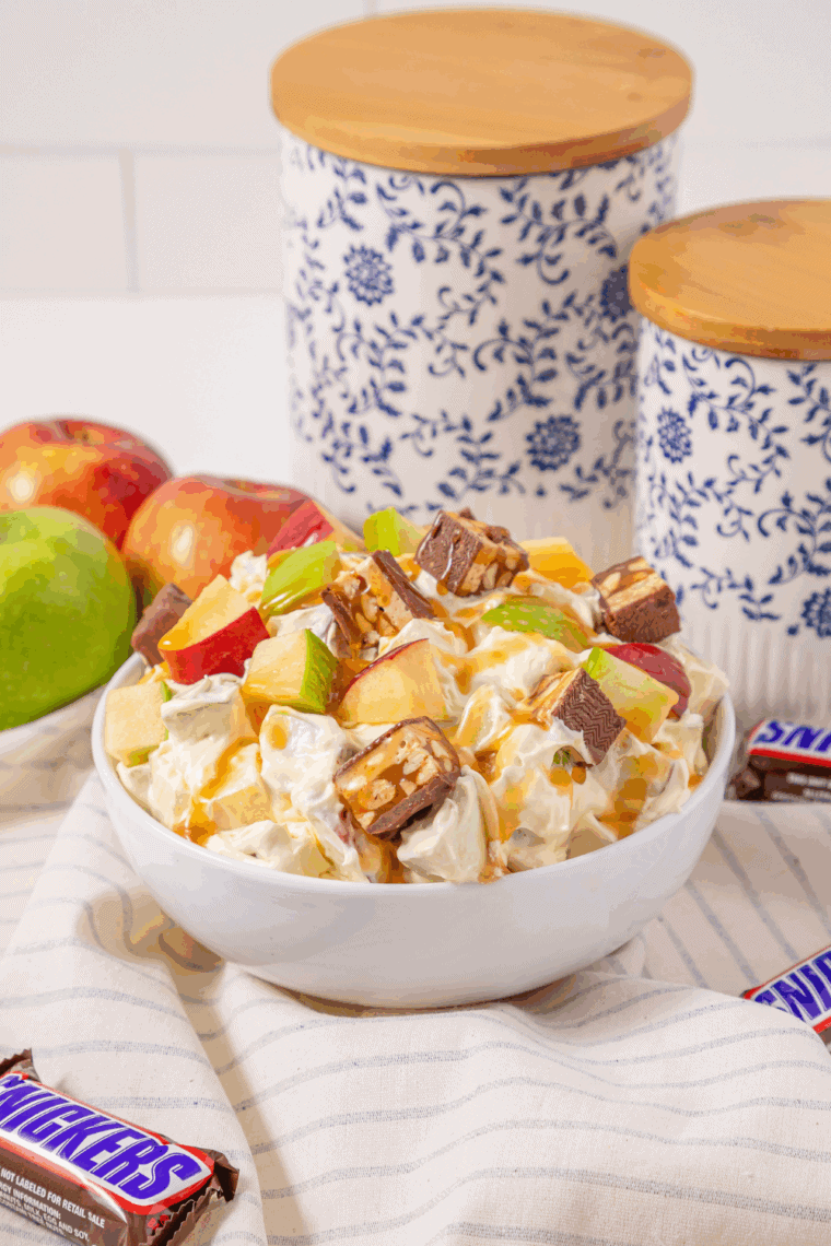Overhead view of Snickers apple salad topped with caramel sauce in a glass serving bowl