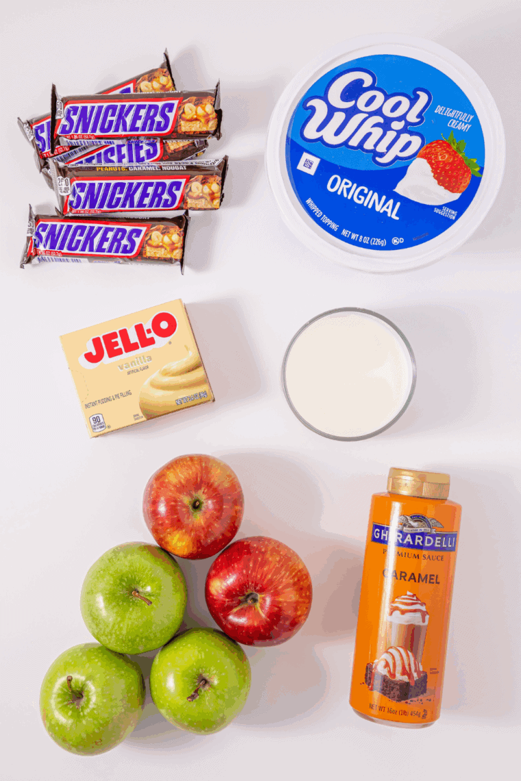 Ingredients for candy bar apple salad: vanilla pudding, milk, Cool Whip, green and red apples, Snickers, and caramel