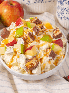 Bowl of Easy Candy Bar Apple Salad with chopped apples, candy bar pieces, and creamy dressing.