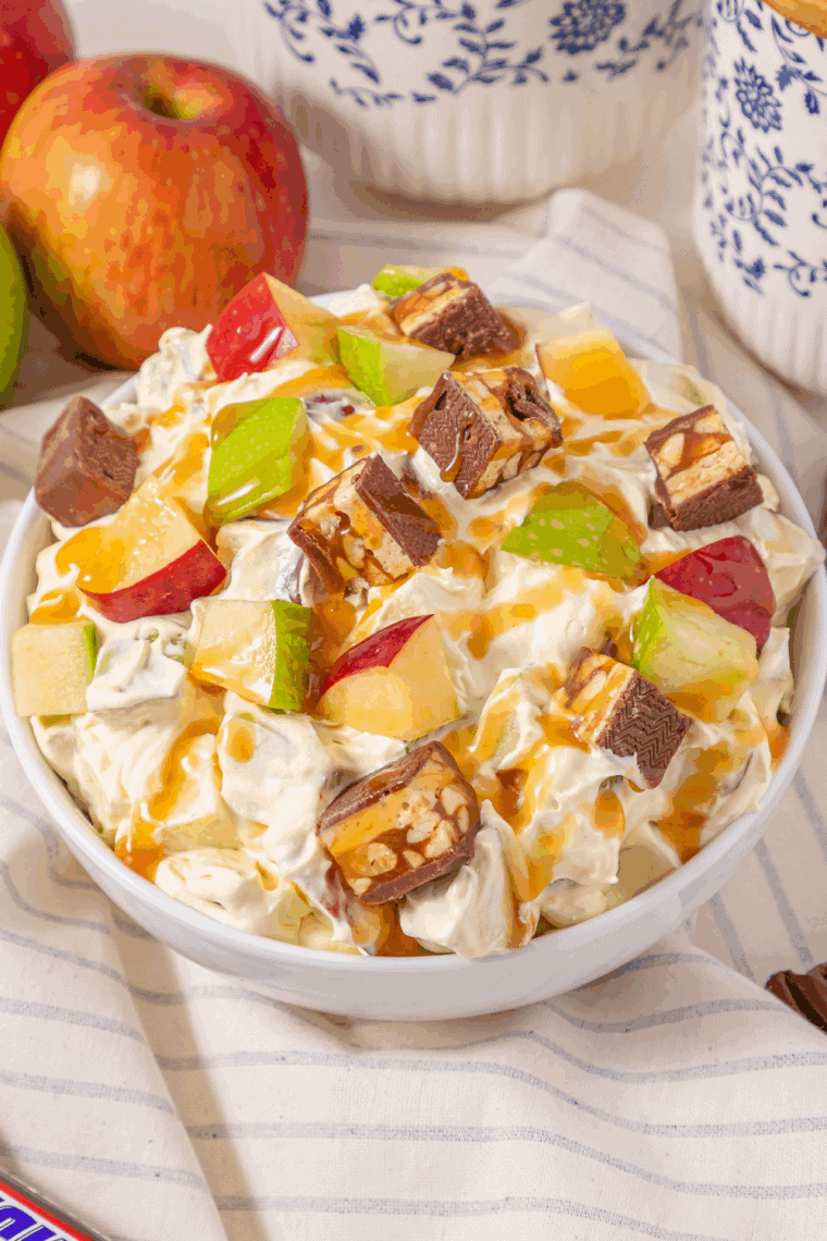 Close-up of finished Snickers apple salad showing apple pieces, candy chunks, and caramel topping