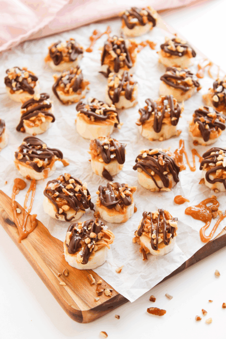 Frozen banana bites coated with chocolate and Snickers pieces on a serving plate, ready to enjoy.
