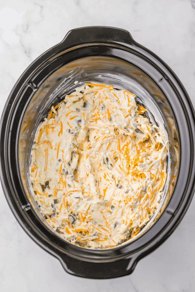 Creamy jalapeño popper dip cooking in slow cooker, being stirred