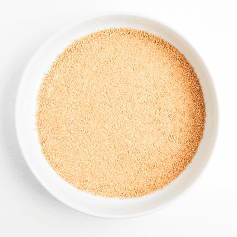 Spreading graham cracker crumbs evenly to form a crust in a serving dish.