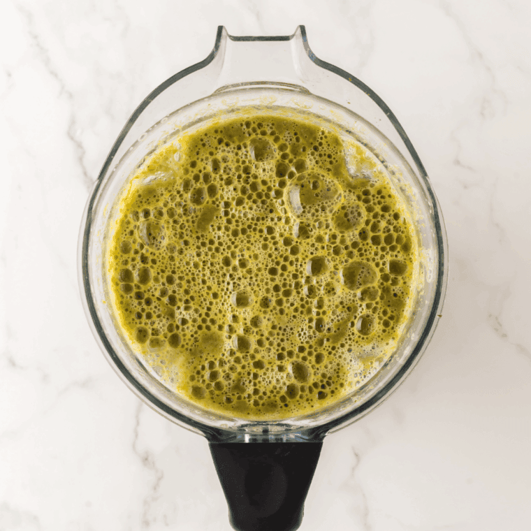 A high-speed blender filled with the cooked asparagus mixture being processed into a vibrant, perfectly smooth green puree.